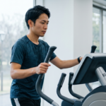 故障中の日本人ランナーが心肺機能維持のためにジムでクロストレーナーを使用する様子