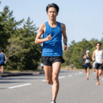 マラソンを走る細く引き締まった体型の日本人男性ランナー。遅筋優位の持久力に優れた体型を表現。