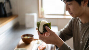 マラソン当日の朝食として、おにぎりを持つ日本人男性の手元のクローズアップ
