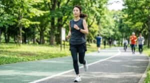 公園のランニングコースを軽快なペースで走り始める、トレーニングウェアを着た日本人女性ランナー